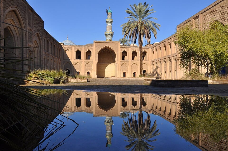 Courtyard view of the ancient Mustansiriya Madrasah university in Baghdad, showcasing traditional Islamic architecture and a reflecting pool.